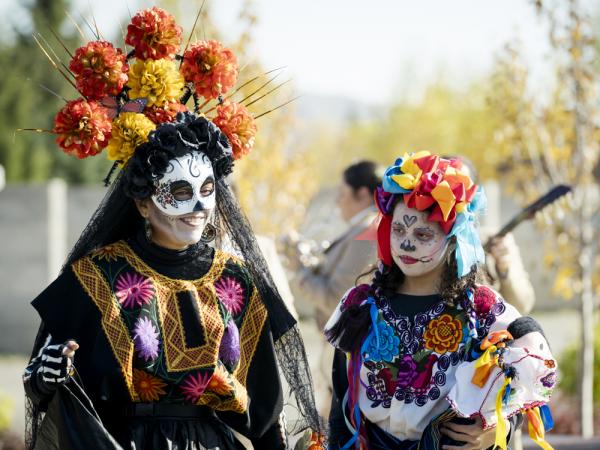 A woman and a child wearing Dia de Los Muertos Regalia