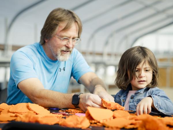 A man and a child creating paper marigolds for dia de los muertos